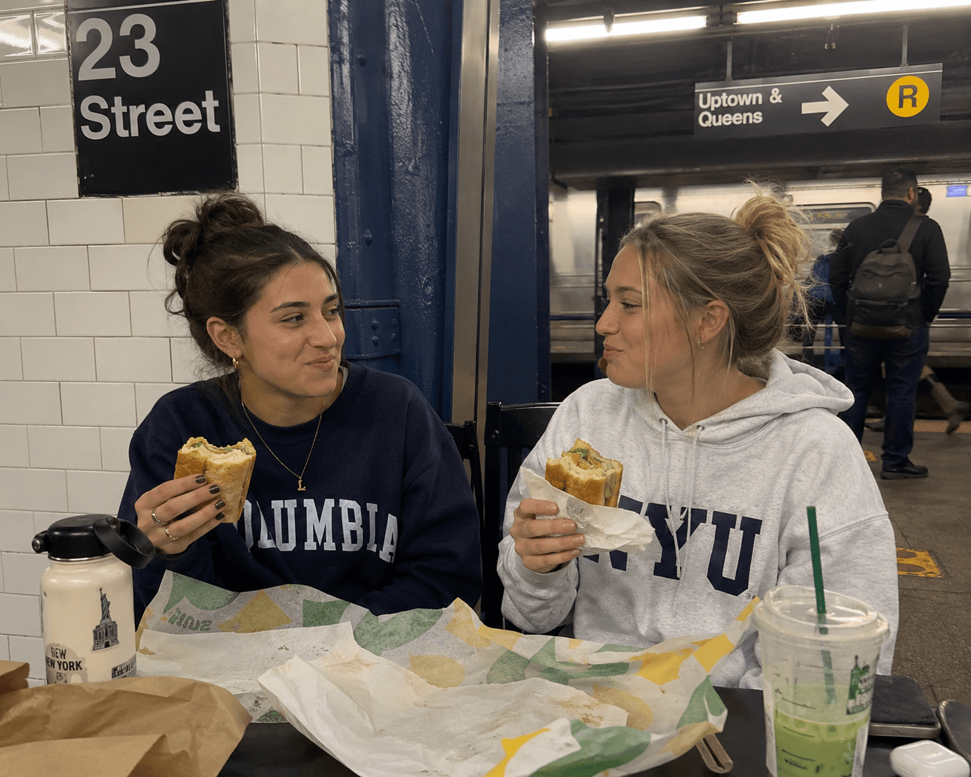 Friends eating sandwiches on a subway platform